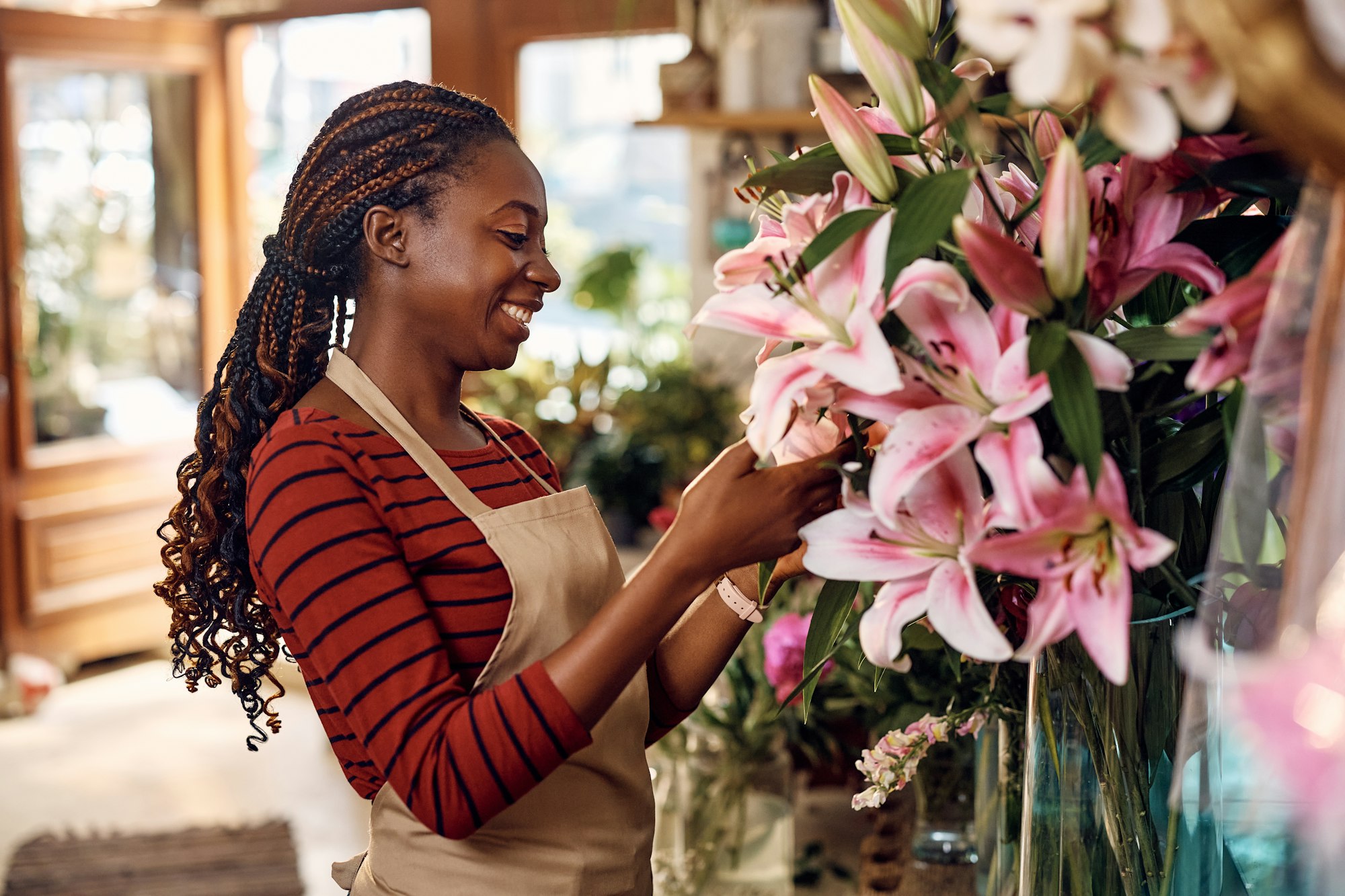 Happy African American woman working at flower shop.